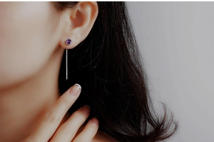 Close-up of S925 sterling silver drop earrings with purple zircon on a female model