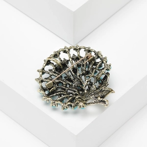 Detail view of the pin mechanism on a vintage bronze filigree brooch with turquoise beads
