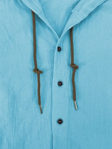 Detail of light blue linen hooded shirt with dark brown drawstrings and button placket