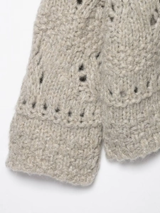 Detailed close-up of beige hollow-out knit fabric with soft wool texture and ribbed edges