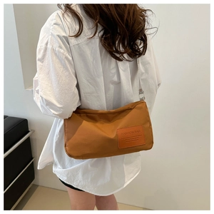 Detail of caramel nylon crossbody bag with side leather fashion label on model