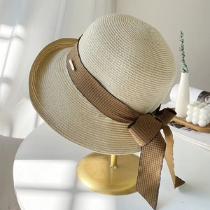 Chapeau de soleil en paille avec nœud à carreaux marron sur un porte-chapeau doré