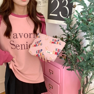 Detailed shot of pink corduroy makeup bag featuring KEEP SMILING print and smiling face