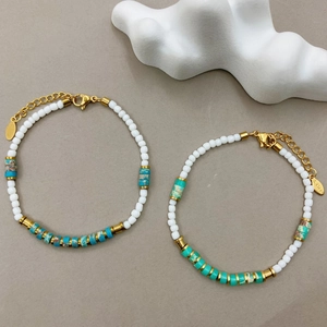 Close-up of beaded bracelet featuring white and turquoise stones with gold clasp