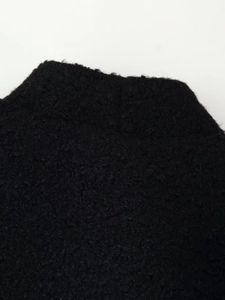 Close-up of premium black thickened wool fabric showing detailed fiber texture on coat