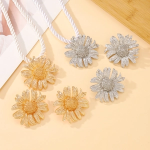 Golden and silver sunflower metal curtain tieback clips set on a neutral background