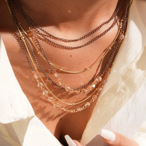 Close-up of multilayer layered necklace with glass beads and gold snake chain on a model