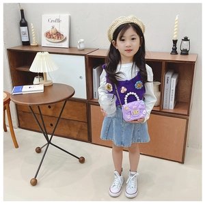 Girl wearing a purple knitted vest with flower decor and a quilted pearl handle handbag