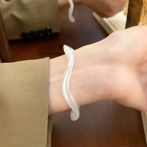 Detail of artistic white wavy resin bracelet with smooth polished finish for women