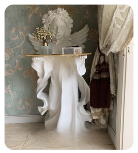 Close-up of white resin angel sculpture holding a golden metal tray for home decor