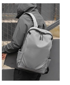 Rear view of a person wearing a grey minimalist Oxford fabric waterproof backpack in the city