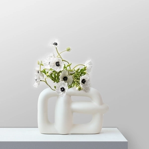 Modern white ceramic abstract geometric vase with matte finish and white flowers