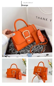Detail of orange lychee texture handbag with golden square buckle and matching mini pouch