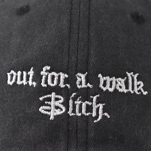 Washed black baseball cap featuring a white embroidered Out for a walk Bitch text design
