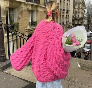 Street view of rose pink chunky knit sweater with cable pattern and loose fit