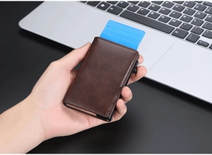 Detail of dark brown leather RFID card holder showing the automatic pop-up mechanism in hand