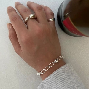 Detail of 925 sterling silver beaded bracelet and minimalist rings on female hand