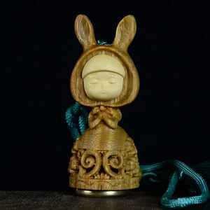 Exquisite hand-carved sandalwood rabbit pendant with green silk tassel on black background