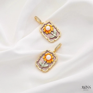 Macro detail of vintage enamel flower pendant with pearl inlay on white silk fabric