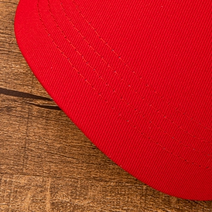 Close-up detail of red baseball cap brim showing premium stitching and fabric texture