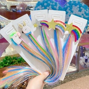 Detail of glitter unicorn and rainbow bow hair clips with colorful wig extensions