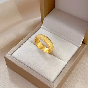 Detailed view of gold minimalist frosted titanium steel ring on beige silk background