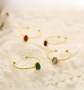 Close-up of four teardrop-shaped natural stone rings on delicate lace fabric