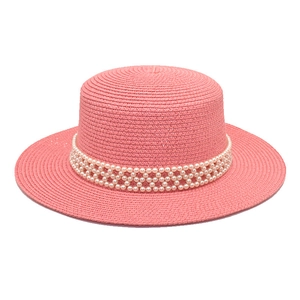 Close-up of pink flat top straw hat featuring triple row pearl band decoration