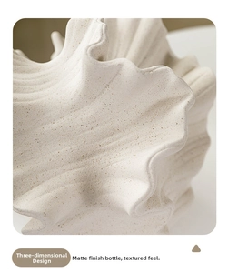 Macro detail of white matte ceramic vase featuring textured grainy surface and wavy edge