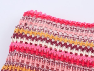 Macro shot of multi-colored hollow crochet knit fabric showing detailed stitching and yarns