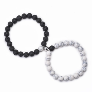 Detail of couple magnetic bracelets with black lava and white turquoise beads in heart shape