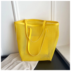 Detail view of yellow mesh tote bag with matching leather handle for summer beach use
