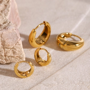 Detailed view of four polished 18k gold-plated hoop earrings on a stone base