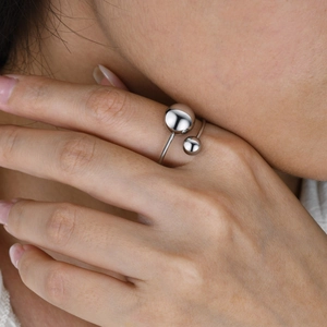 Detailed view of a silver titanium steel open ring with two polished spheres on a finger