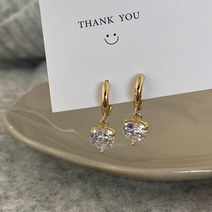 Detail of gold heart zircon hoop earrings on a decorative thank you card display