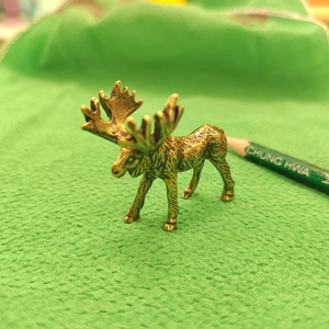 Macro shot of vintage brass elk figurine showing detailed antlers and metallic texture