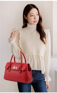 Detailed view of red crocodile pattern shoulder bag with silver clasp and woven handle