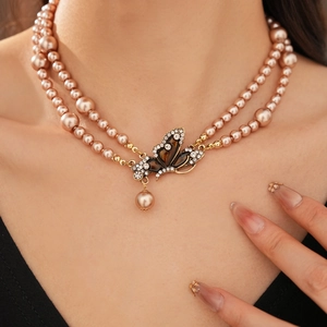 Close-up of double-layer champagne pearl necklace with rhinestone butterfly pendant