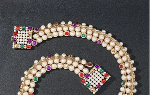 Detailed macro of golden mesh chain belt with white pearls and colorful square rhinestones