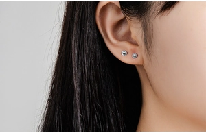Macro shot of minimalist s925 silver ball screw back earrings on model earlobe