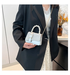 Silver sequin crossbody bag with pearl handle and gold chain strap on shoulder