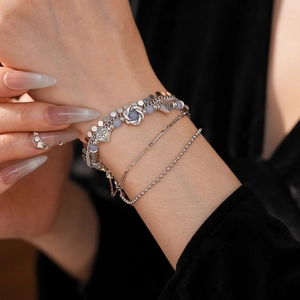 Close-up of vintage multilayer silver bracelet with blue beads and floral charms on wrist
