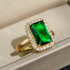 Macro shot of a vintage gold ring featuring a rectangular green gem and halo diamonds