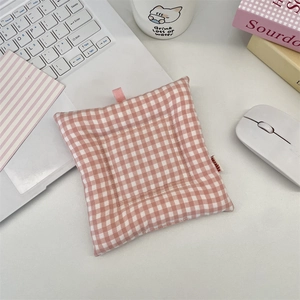 Vue détaillée d'un sous-verre en tissu matelassé à carreaux roses sur un bureau