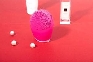 Soft pink silicone facial cleanser with dense bristles shown with elegant pearl accents