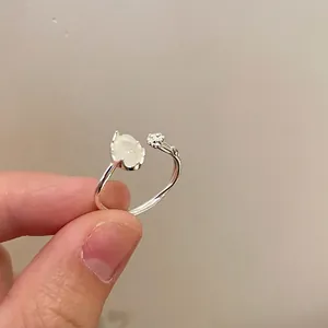 Detailed close-up of adjustable silver ring with cat-ear moonstone and metal flower charm