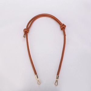Close-up of adjustable brown leather shoulder strap with gold hardware and knotted detail