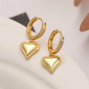 Close-up of gold-plated heart earrings with small crystals and woven texture edges