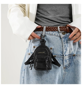 Macro detail of mini black leather coin pouch keychain on blue denim jeans loop