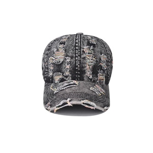 Macro detail of distressed black denim cap with ripped holes and colorful stitching